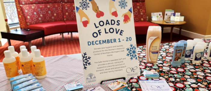 Photo of inside the Petoskey District Library showing a table set up for the Loads of Love initiative that seeks donations of laundry items for the local Women's Resource Center.