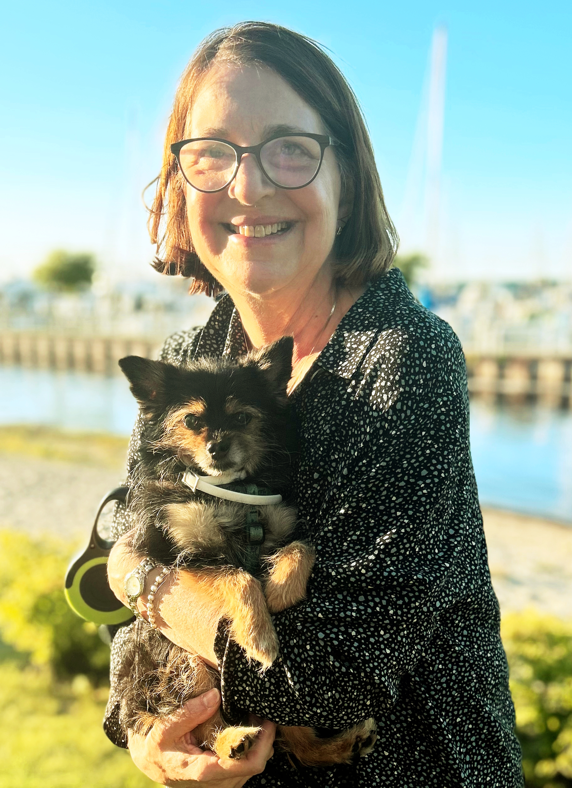 Photo of Lisa Scholl holding her dog down with Petoskey Harbor in the background